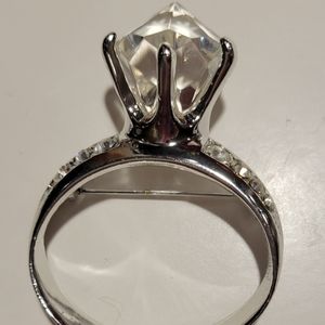 Silver tone diamond ring style brooch.